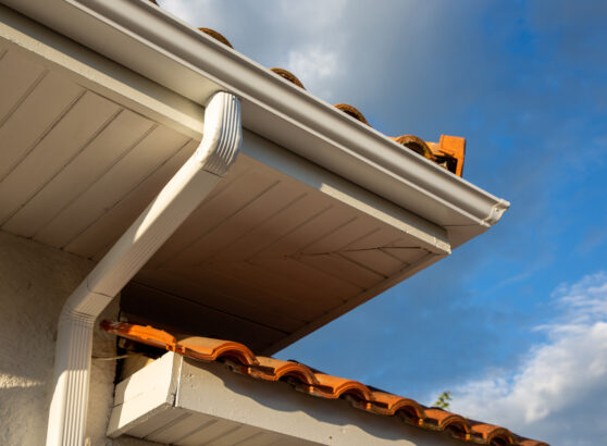 House corner with white planks siding and roof with steel gutter