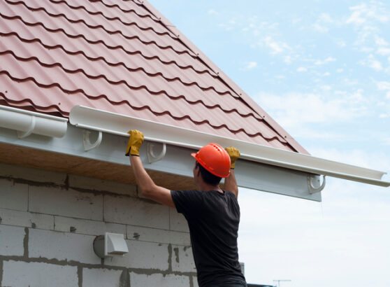 worker installs the gutter system on the roof