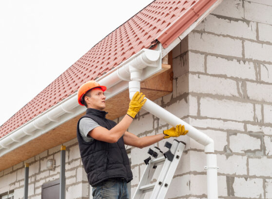 construction worker installs the gutter system on the roof