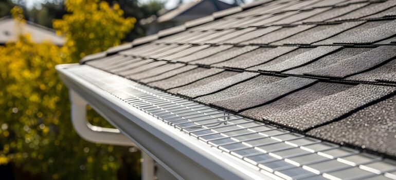 residential asphalt shingle roof and gutter guard installation | White seamless rain gutter with leaf protection mesh screens