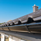 A metal, black gutter on a roof covered with ceramic tiles